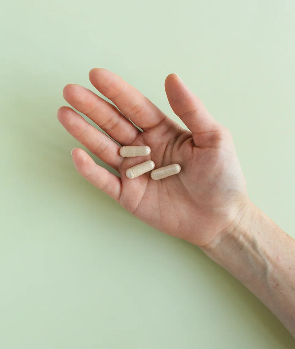 Hand holding a Daily Response multivitamin capsule